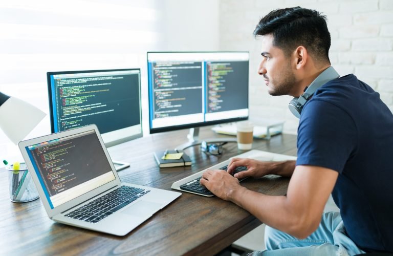 Side view of attractive Hispanic software developer programming using computer while working from home